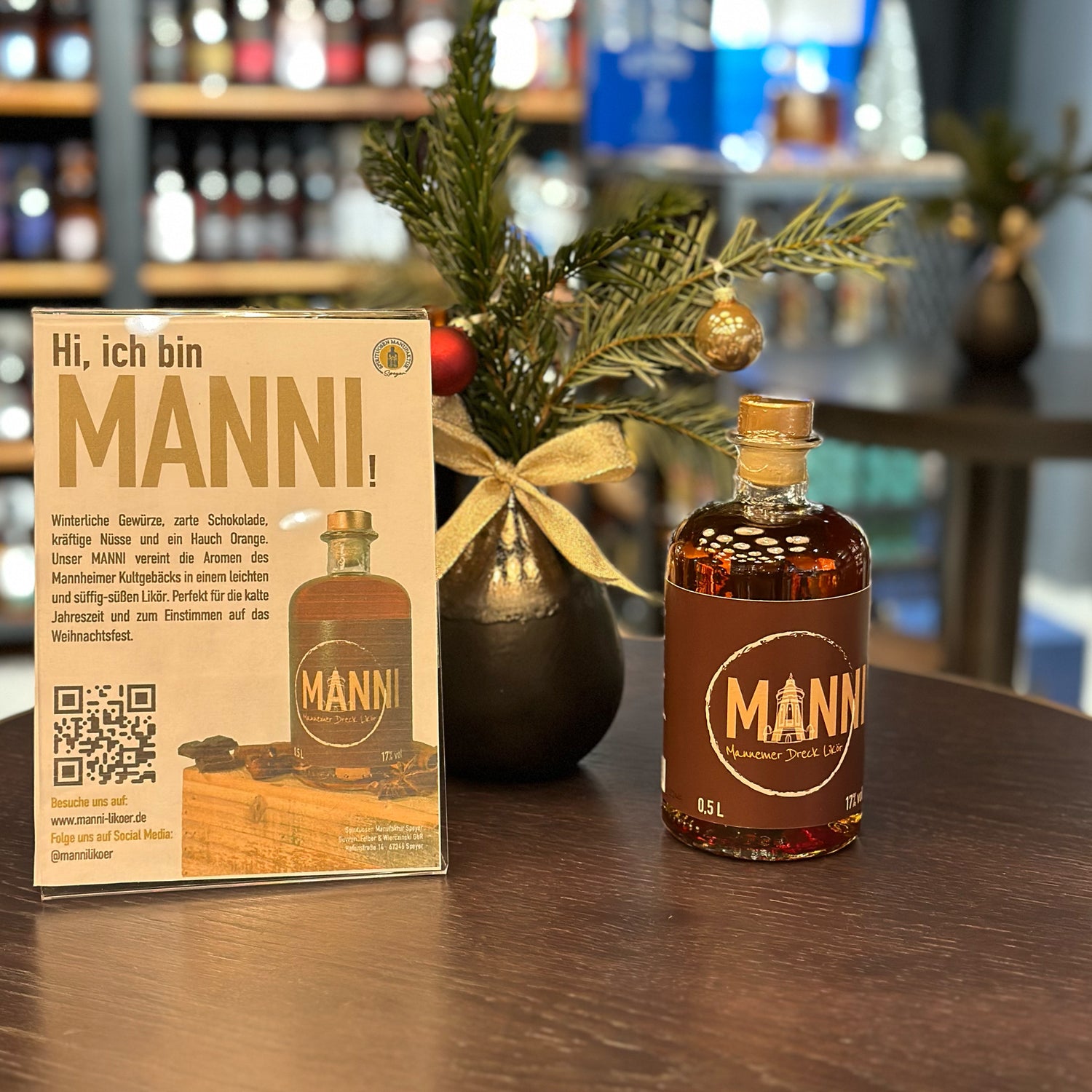 Flasche Mannemer Dreck Likör auf dem Tisch mit Tannenzweigen und Tischaufsteller