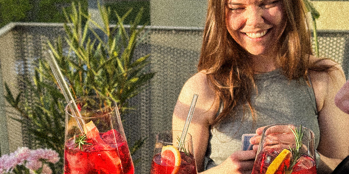 Drei lachende Personen stoßen mit GRANADA NIGHTS Spritz an, warme Abendstimmung in geselliger Runde im Freien