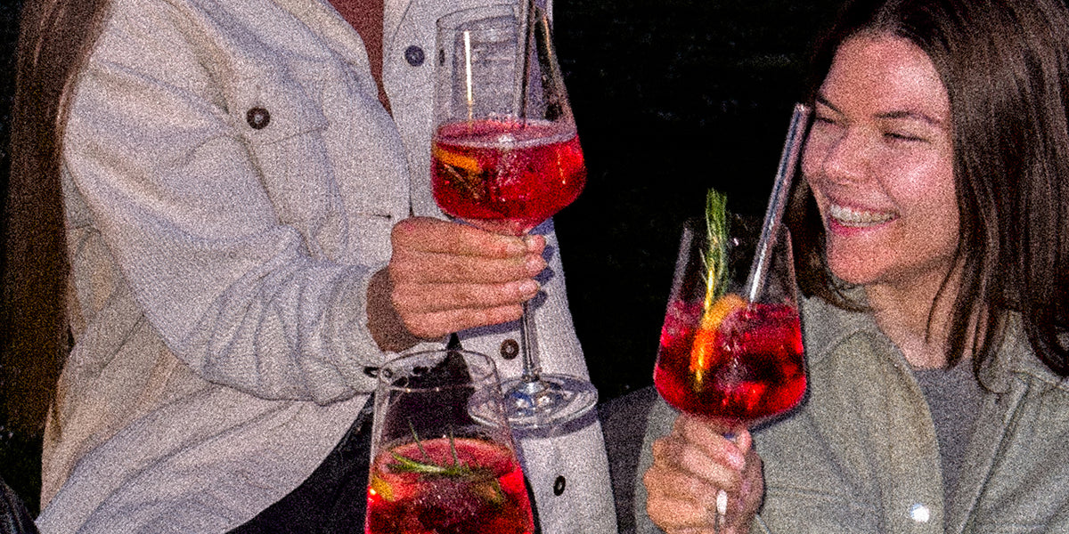 Drei lachende Personen stoßen mit GRANADA NIGHTS Spritz an, Nachtstimmung