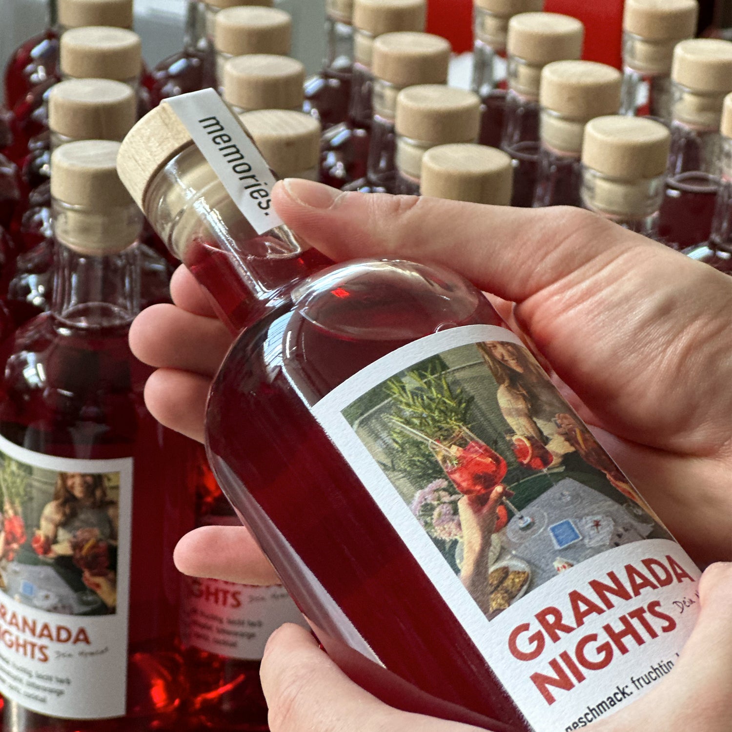 Zwei Hände halten eine Flasche GRANADA NIGHTS, im Hintergrund weitere Flaschen